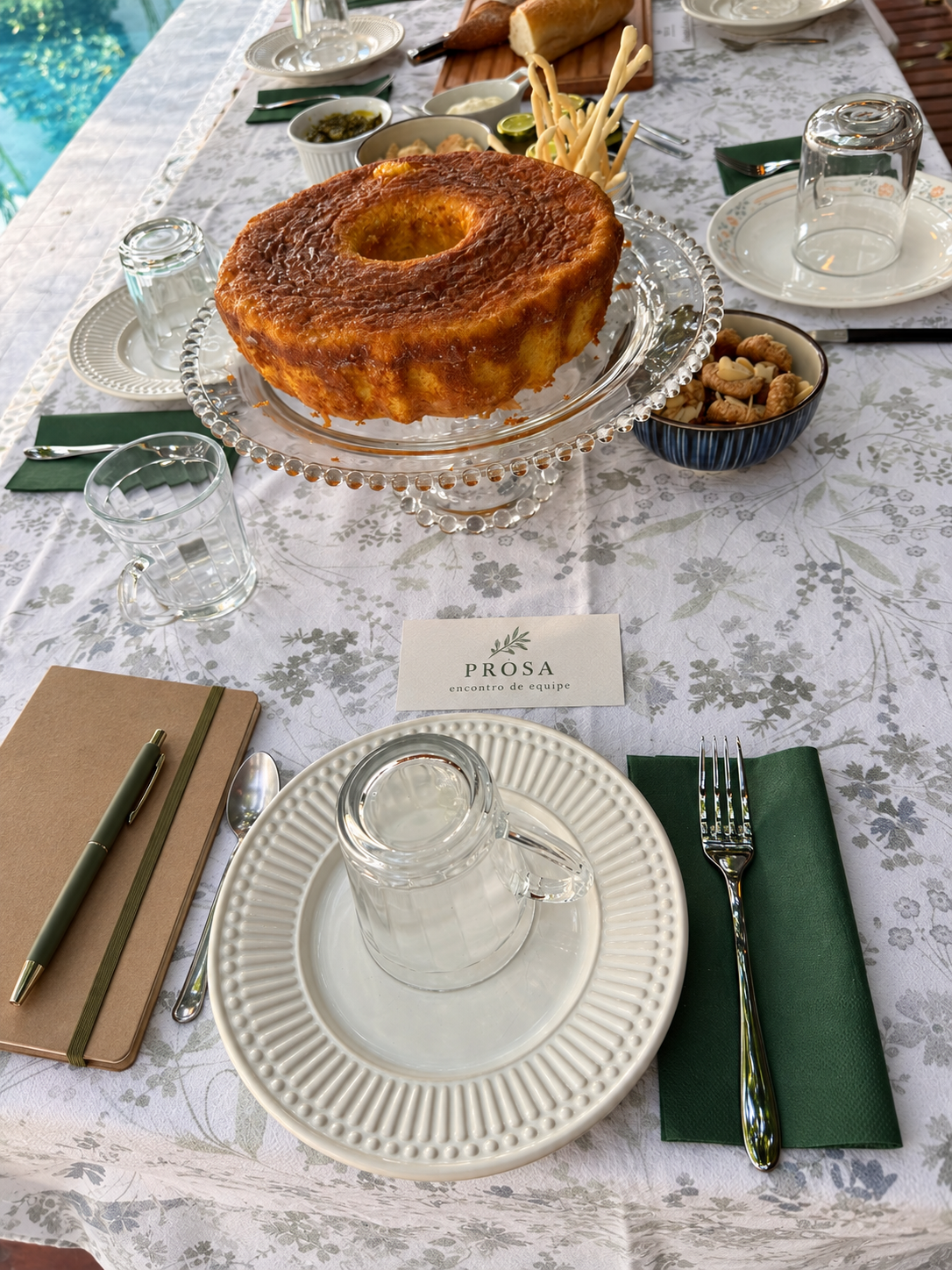 Lugar à mesa preparado com caderno, caneta, café e comida